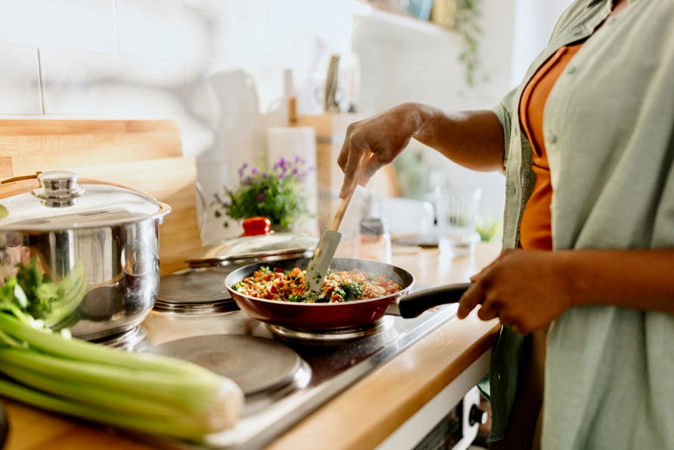 woman cooking a colourful and nutritious quinoa stir fry with mixed vegetables and a drizzle of olive oil.