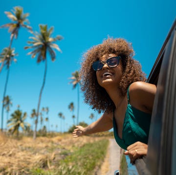 Woman looking out the car window tropical beach road trip