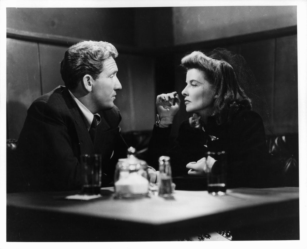 Spencer Tracy and Katharine Hepburn having drinks together at small table in a scene from the film 'Woman Of The Year'