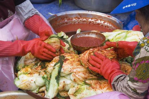 Women wearing red gloves preparing Kimchi