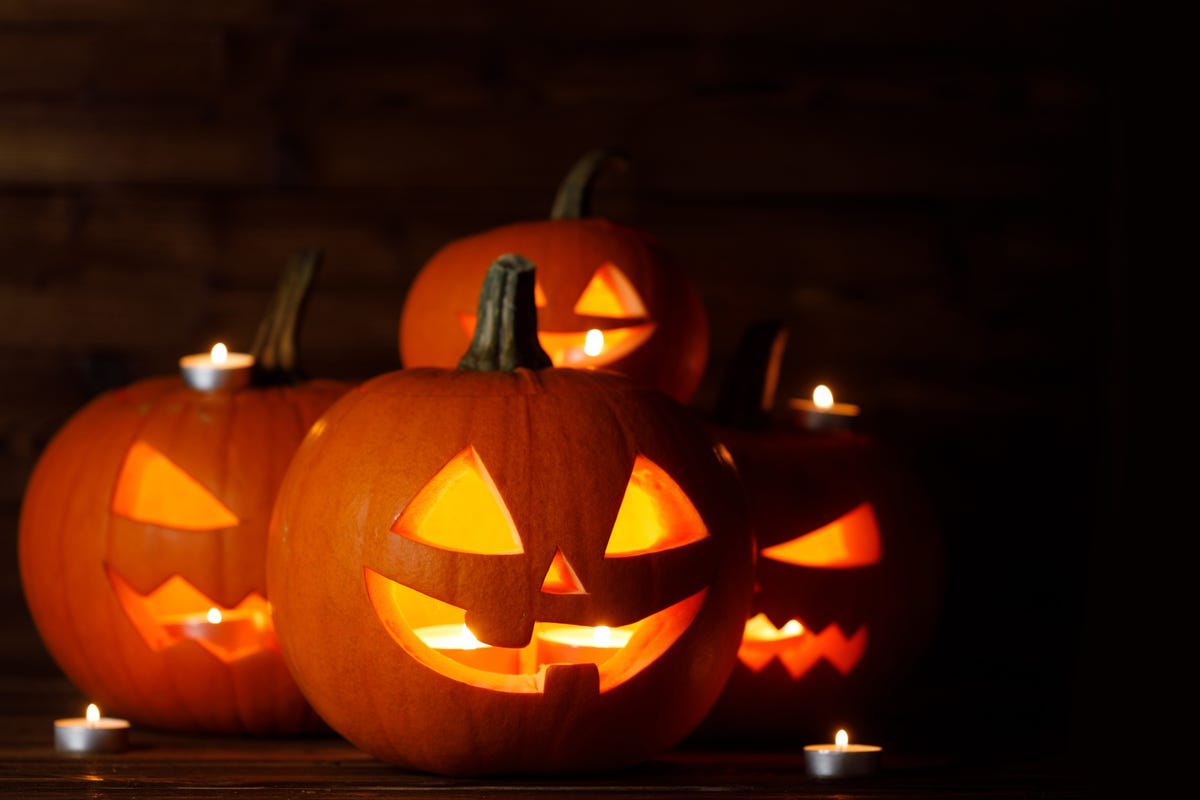 pumpkin carving, group of glowing halloween pumpkin lanterns and burning candles on dark wooden background