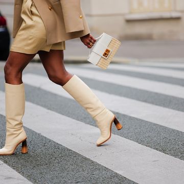 a woman crossing the street in cream heeled boots