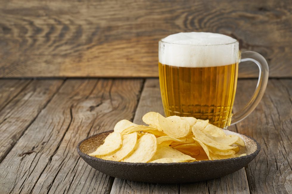 crisp in bowl with beer in glass, top view, wooden background, copy space