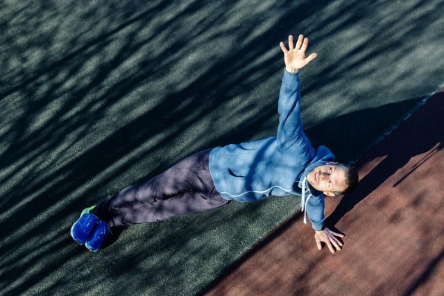 side plank pose man doing a workout on the muscles of the core on the sports field in the park