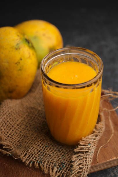vaso de cristal con aliño de mango y mangos frescos al fondo