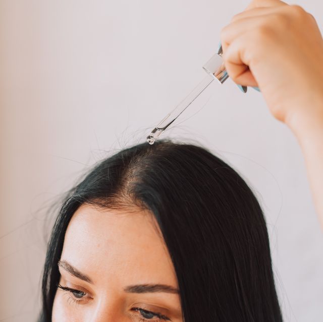 lady applying serum on scalp and hair from pipette