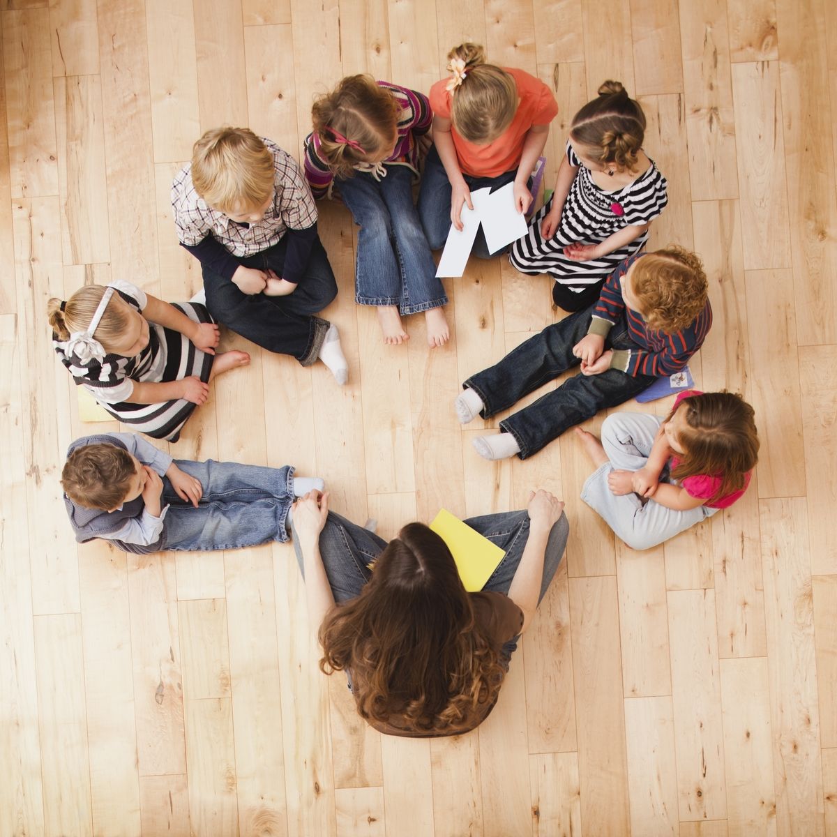 children 2, 3, 4 and 5 sitting in circle around teacher, directly above