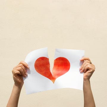 woman's hands tearing a red heart