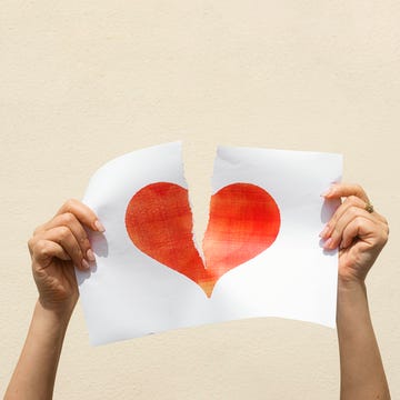 Broken Heart Concept woman's hands tearing a red heart