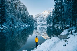 man admiring a mountain lake in winter scenery