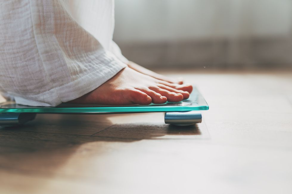 female feet standing on electronic scales for weight control on wooden background the concept of slimming and weight loss