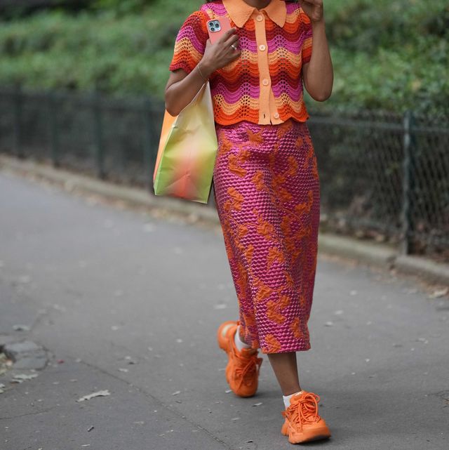 paris, france june 21 a guest wears neon pink sunglasses, pink earrings, a red  orange  pink wavy striped print pattern braided wool short sleeves  shirt neck buttoned polo shirt, a neon pink embossed polka dots print pattern with embroidered orange pattern long tube skirt, a green and orange tie and dye print pattern large shoulder bag, white socks, orange shiny leather sneakers , outside rhude, during the menswear springsummer 2024 as part of paris fashion week on june 21, 2023 in paris, france photo by edward berthelotgetty images