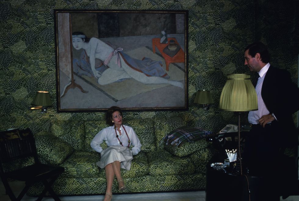 french born businesswoman helene rochas 1927   2011, president of marcel rochas perfume and fashion house, listens to an unidentified man as she sits on a sofa in her elaborately decorated apartment, new york, new york, june 1979 photo by susan woodgetty images