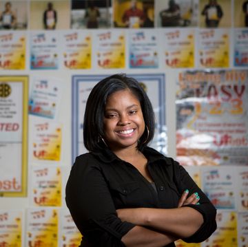 a person smiling in front of a wall of posters