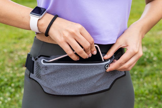 fitness runner woman getting ready for running with smartwatch and smartphone holder fanny pack waist belt athlete woman wearing wearable tech activity tracker for sport exercise activity
