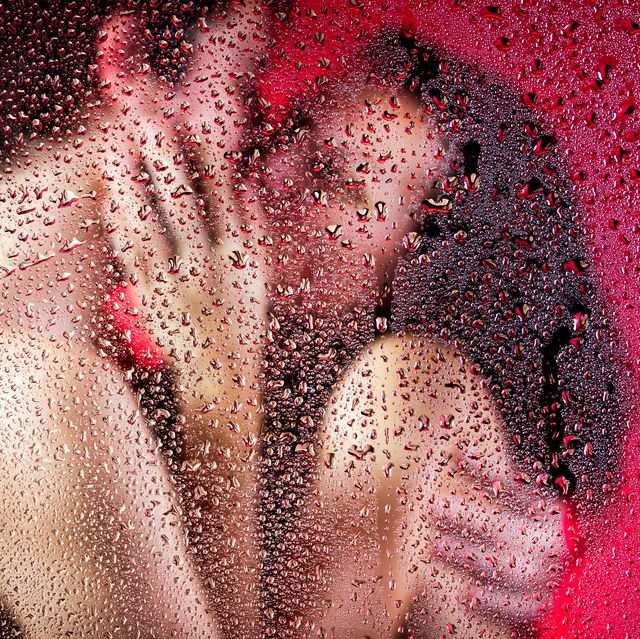 beautiful couple kissing and huging behind wet glass