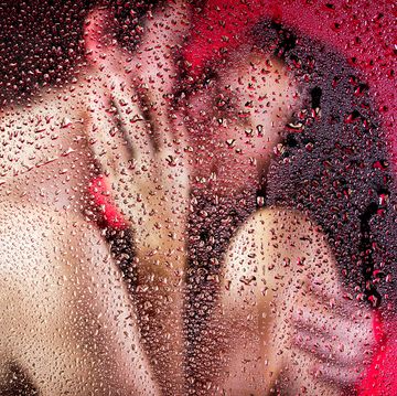 beautiful couple kissing and huging behind wet glass