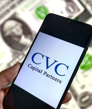 telefoon met logo van cvc capital partners, met op achtergrond hoop dollarbiljetten