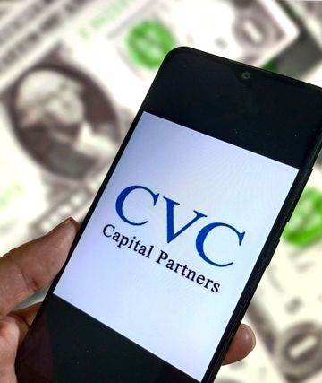 telefoon met logo van cvc capital partners, met op achtergrond hoop dollarbiljetten