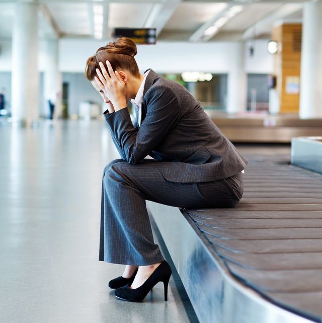Frustrated Businesswoman Sitting at Baggage Claim