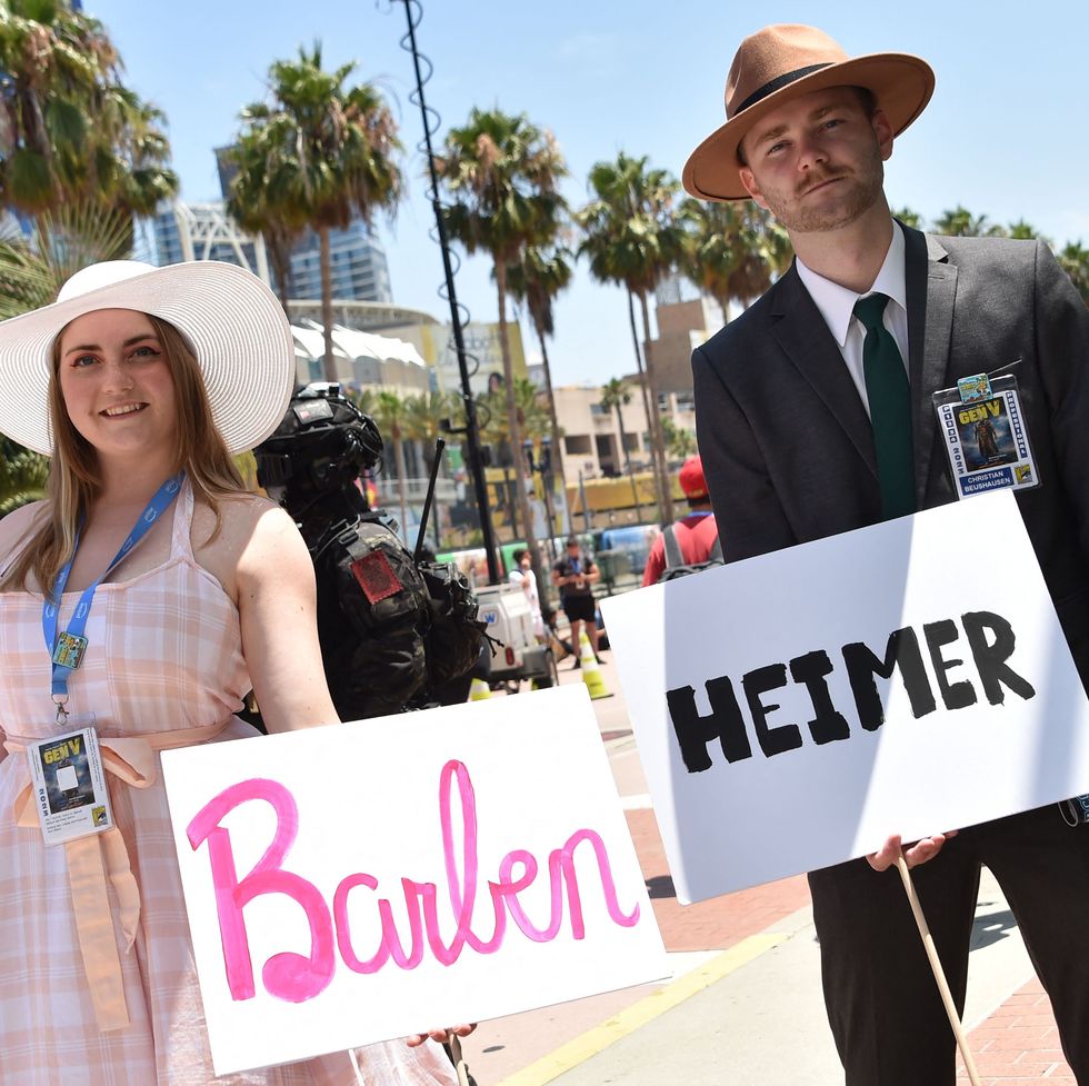 cosplayers hold barbenheimer signs outside the convention center during san diego comic con international in san diego, california, on july 21, 2023 photo by chris delmas afp photo by chris delmasafp via getty images