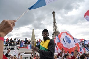 jamaican sprinter usain bolt holds the olympic torch during the torchs presentation on the river seine, as the landmark eiffel tower is seen, in paris, on july 25, 2023, ahead of the paris 2024 olympic and paralympic games photo by alain jocard afp photo by alain jocardafp via getty images