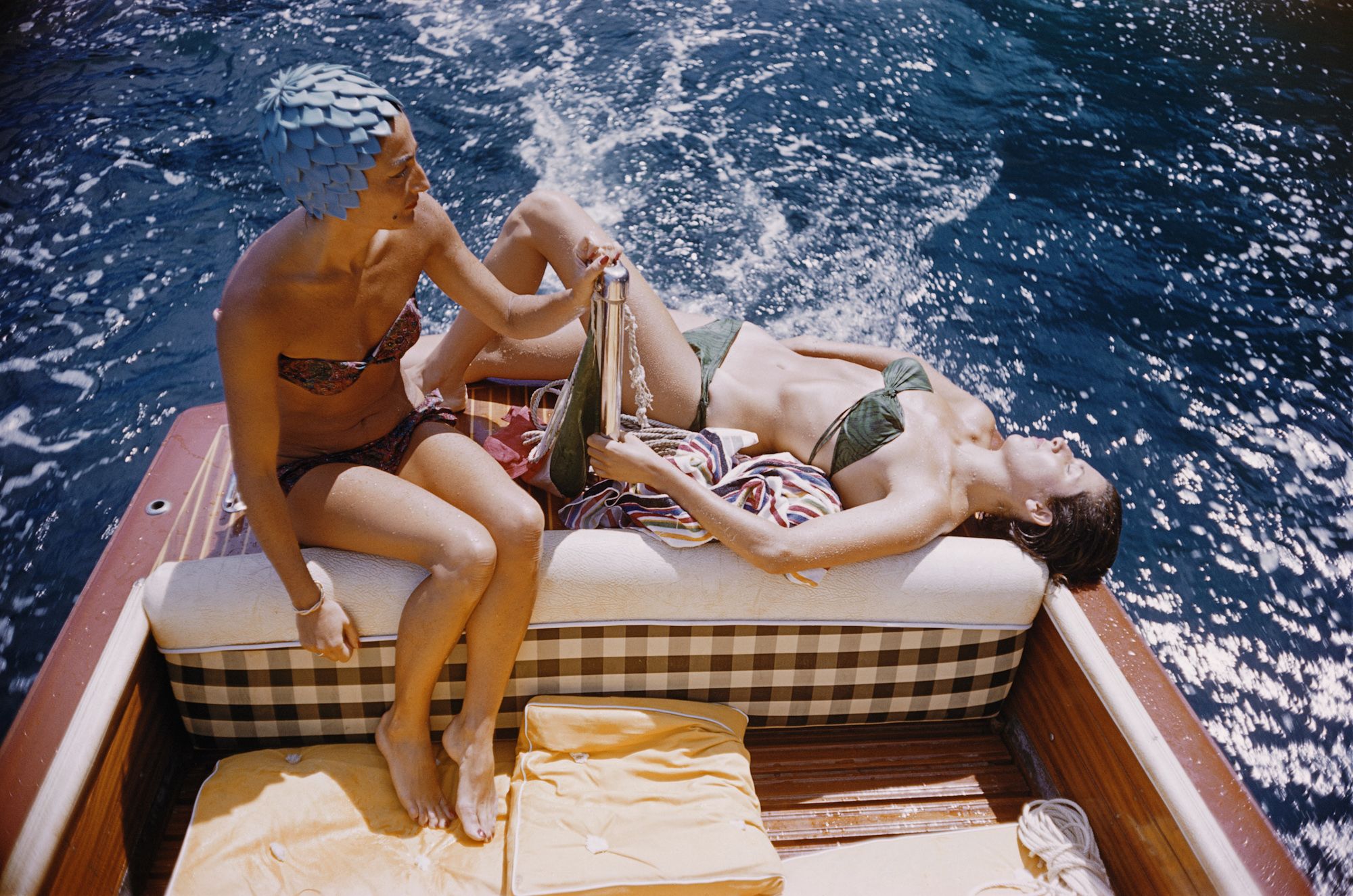 carla vuccino, wearing a swimming cap, and a sunbathing marina rava, both wearing bikinis as they sit on the rear of a boat, on the waters off the coast of the island of capri, italy, 1958  photo by slim aaronsgetty images