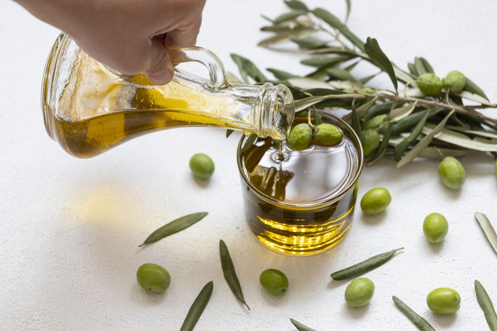 a hand pouring olives into a jar
