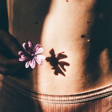 young woman belly with flower naked abdomen with many birthmarks