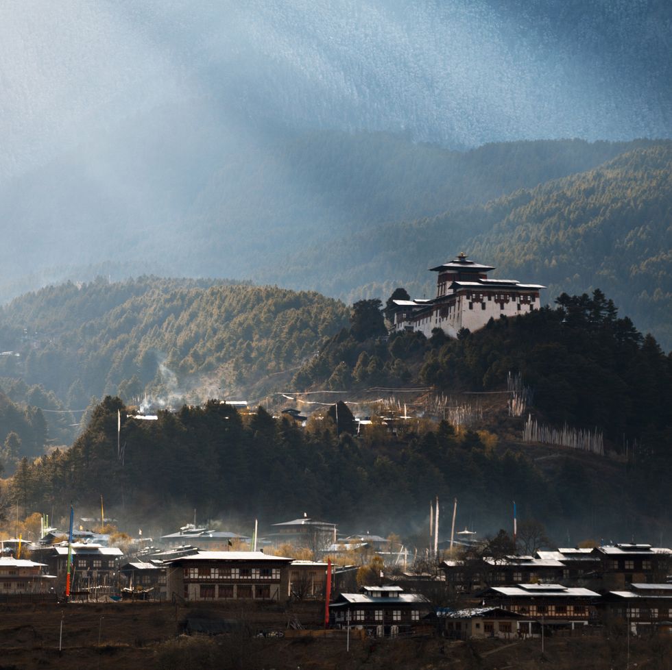 morning sunrays over jakar town and dzong, fog rising from the town lit up