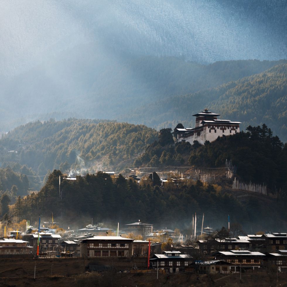 morning sunrays over jakar town and dzong, fog rising from the town lit up