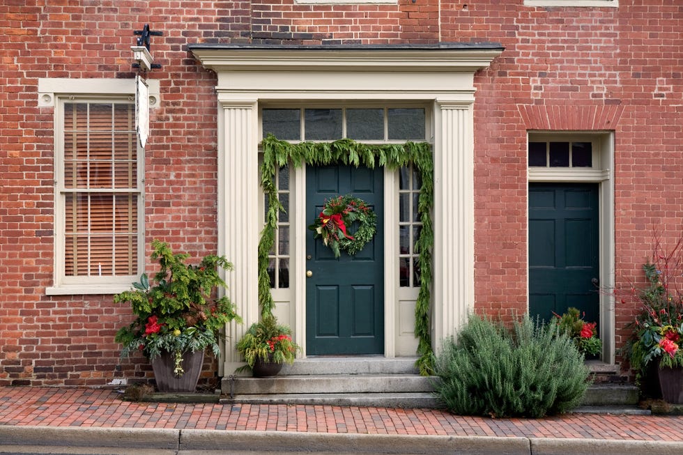 Christmas decorations on front porch of house and townhouse along street