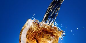 Cola with a large splash, isolated on blue