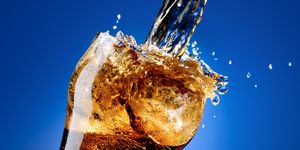 Cola with a large splash, isolated on blue