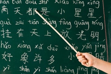 girl pointing at blackboard with her chinese lesson