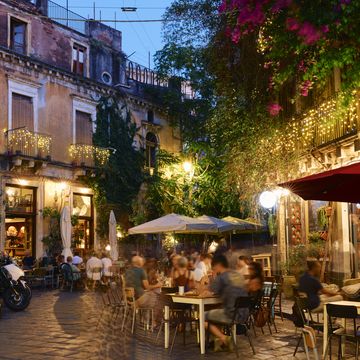 italy, sicily, catania, people dining and socialising outside at dusk
