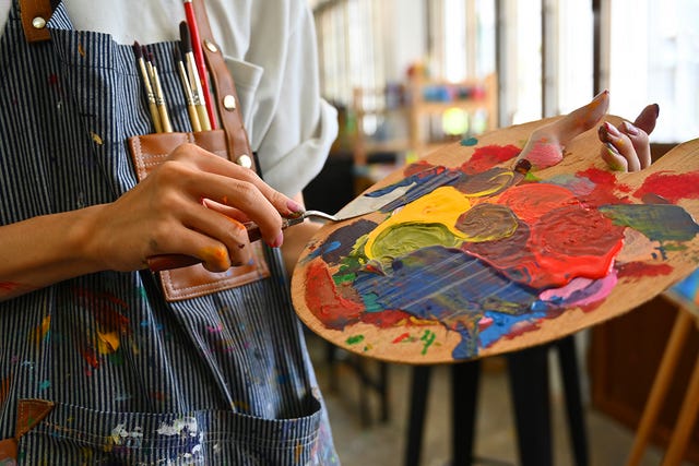 artist holding a palette with vibrant paint colors