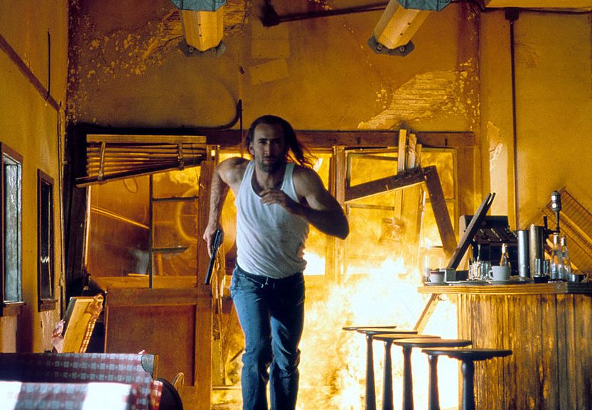 nicolas cage running through a burning building while holding onto a gun in a scene from the film con air, 1997 photo by touchstone picturesgetty images