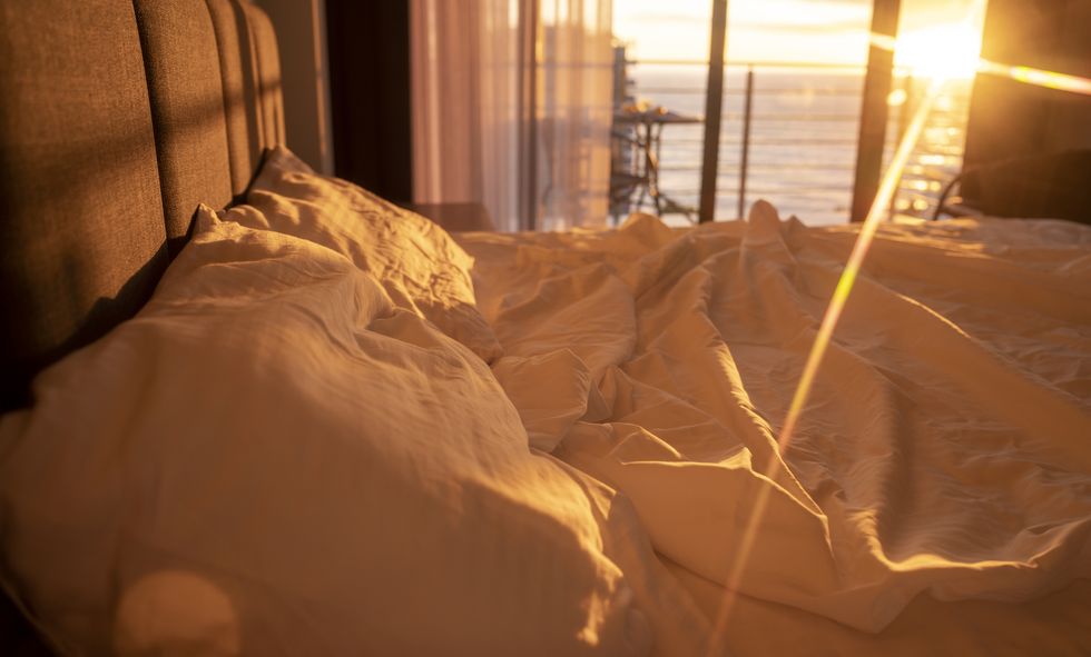bed with white pillows and bed linen in sunlight in the morning bedroom details