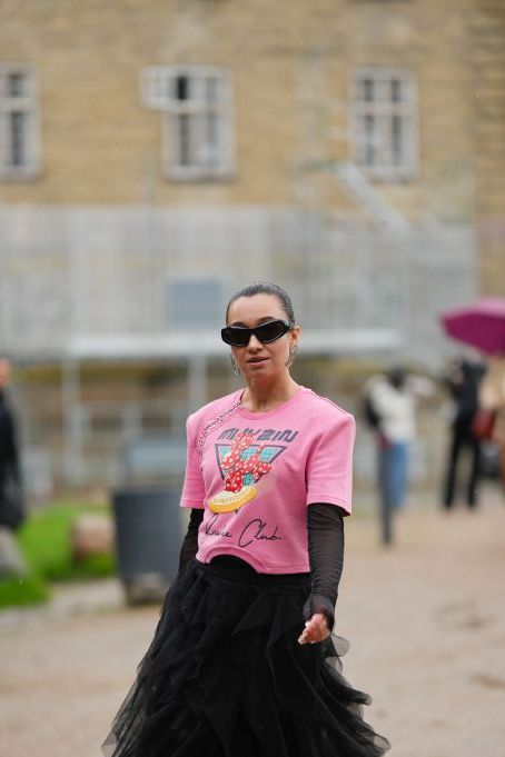 copenhagen, denmark august 09 a guest wears black sunglasses, silver earrings, a pink with black blue red print pattern t shirt, a black long sleeves t shirt, a black ruffled tulle long skirt, a neon pink shiny leather handbag, silver shiny leather block heels ankle boots , outside operasport, during the copenhagen fashion week springsummer 2024 on august 09, 2023 in copenhagen, denmark photo by edward berthelotgetty images