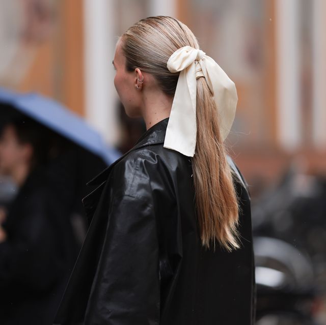 copenhagen, denmark august 09 a guest seen wearing silver earrings, cream white satin and silk ribbon as hair accessory, black leather long coat, outside the garment, during the copenhagen fashion week springsummer 2024 on august 09, 2023 in copenhagen, denmark photo by jeremy moellergetty images