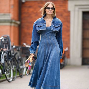 copenhagen, denmark august 10 a guest wears black sunglasses, a gold chain necklace, a blue denim micro cropped jacket, a blue denim embossed striped pattern shoulder off long ripped dress, a brown shiny leather braided leather jodie handbag from bottega veneta, camel shiny leather varnished platform high heels shoes from chanel , outside mark kenly domino tan, during the copenhagen fashion week springsummer 2024 on august 10, 2023 in copenhagen, denmark photo by edward berthelotgetty images