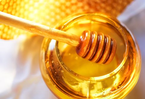 Honey in a glass jar next to honeycombs