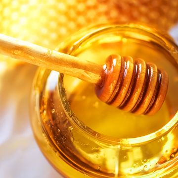 honey dipper on the bee honeycomb background honey tidbit in glass jar and honeycombs wax