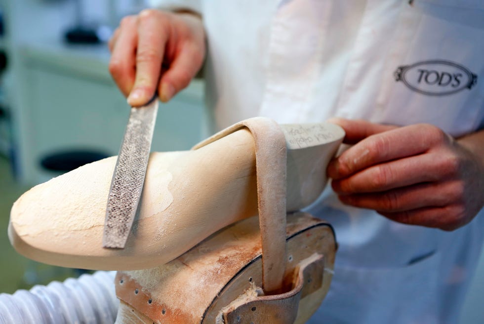 craftsman shaping a wooden shoe mold with a rasp