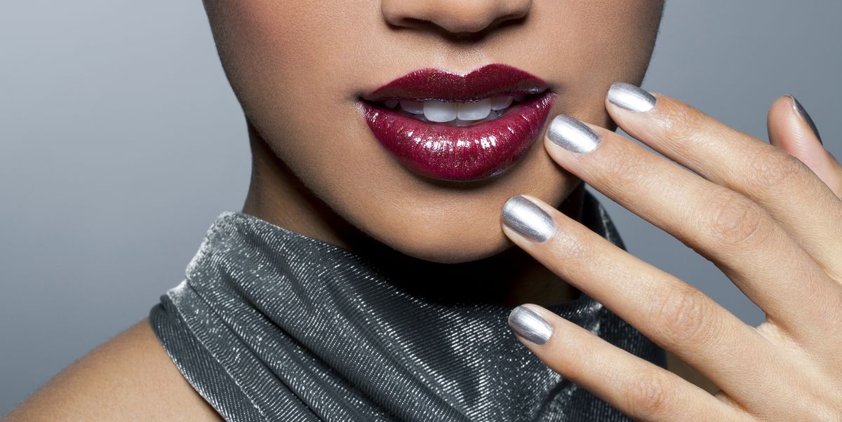 young african american woman in a glamorous silver top with red lips, silver eye shadow and silver nail polish holding her hand close to her lips, portrait