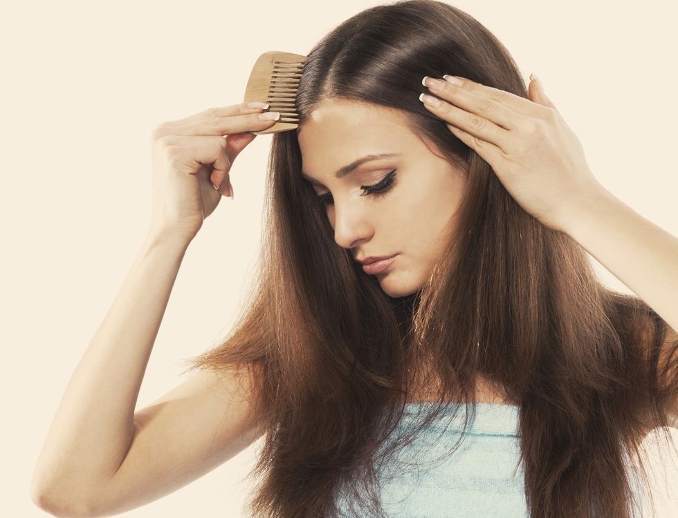 young brunette lady combing her beautiful long hair isolated white
