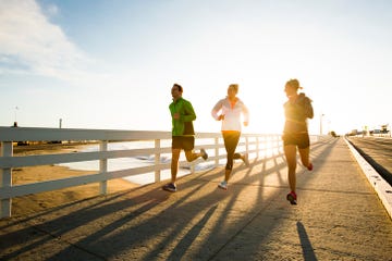friends running a boardwalk near the pacific ocean