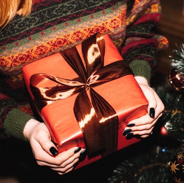 Young woman holding Christmas Present standing by Christmas Tree at home 12 days of christmas meaning facts
