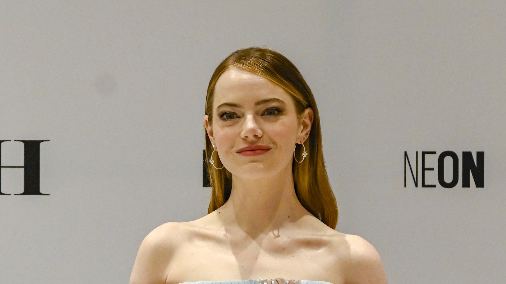 Emma Stone seen wearing a white top with black trousers with a